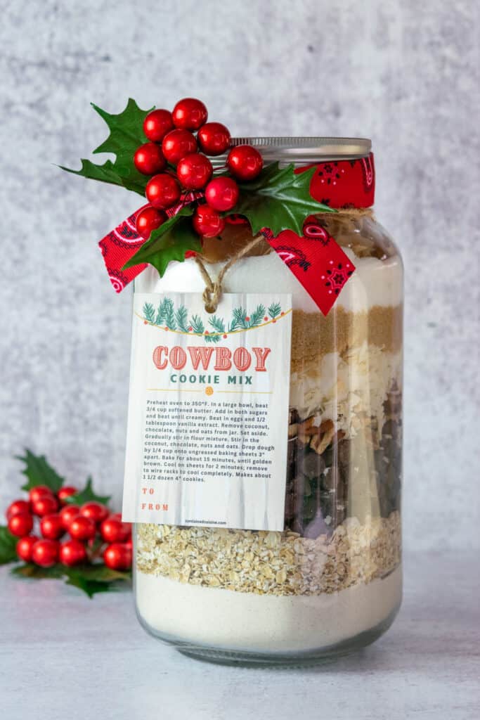 Half gallon mason jar layered with cowboy cookie mix ingredients ready for gift giving.