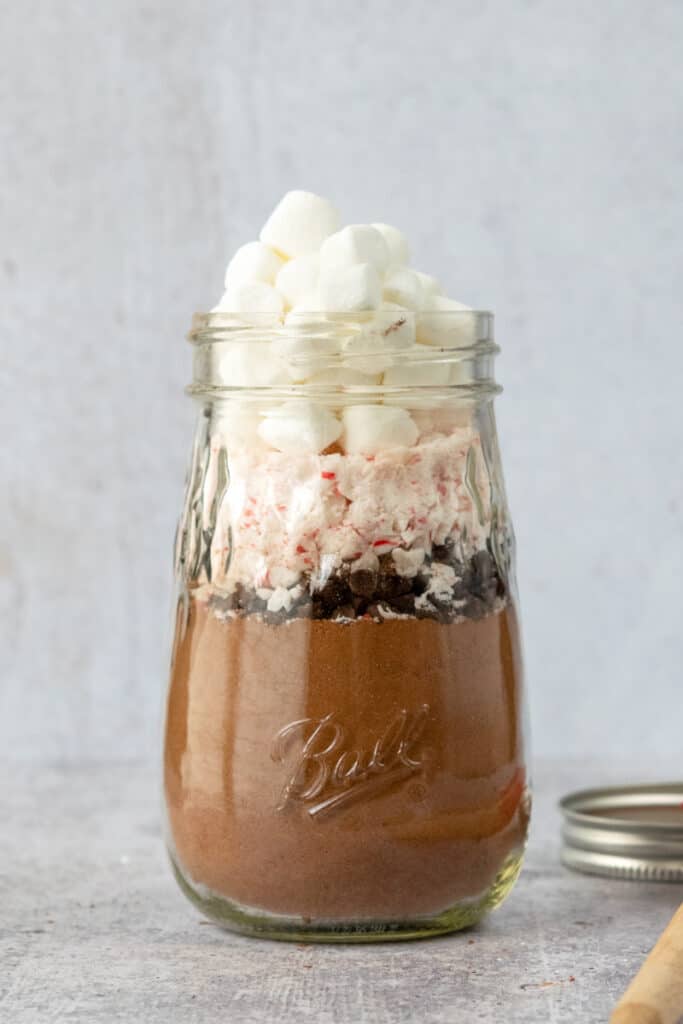 Mason jar layered with hot cocoa mix, chocolate chips, crushed peppermint candy and marshmallows.