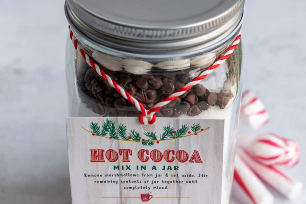 Homemade hot chocolate mix in a jar layered with chocolate chips and marshmallows on top.