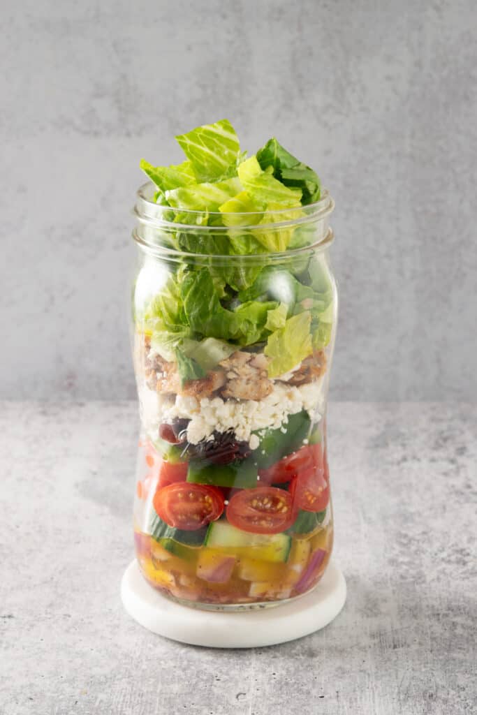 Greek Salad layered in a mason jar for a convenient meal.