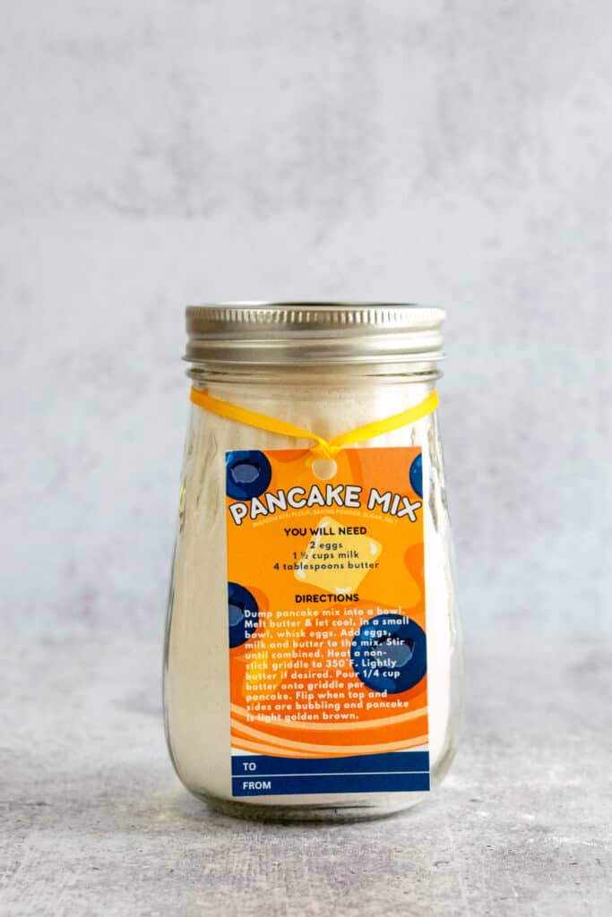 Homemade pancake mix in a jar with a decorative gift tag that shows additional ingredients needed and directions for cooking the pancakes.