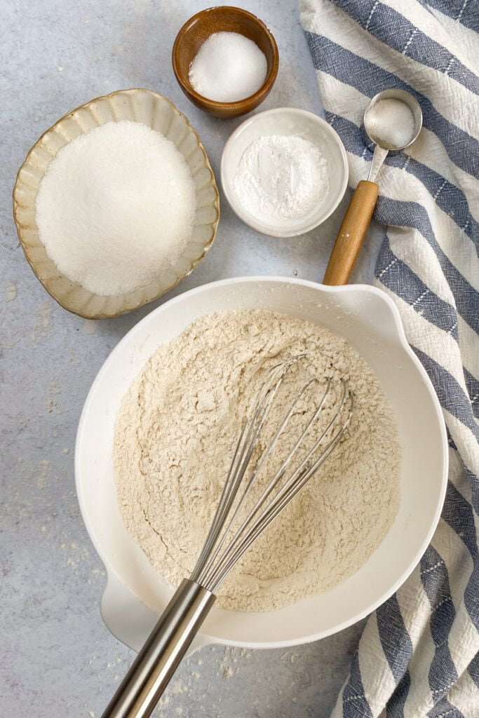 The ingredients all whisked together with a whisk sitting in the bowl of the flour mixture.