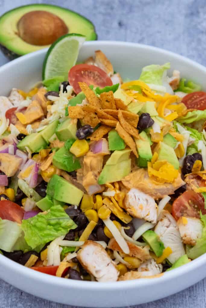 Southwest Salad in a bowl, topped with diced avocado and tortilla chip strips.