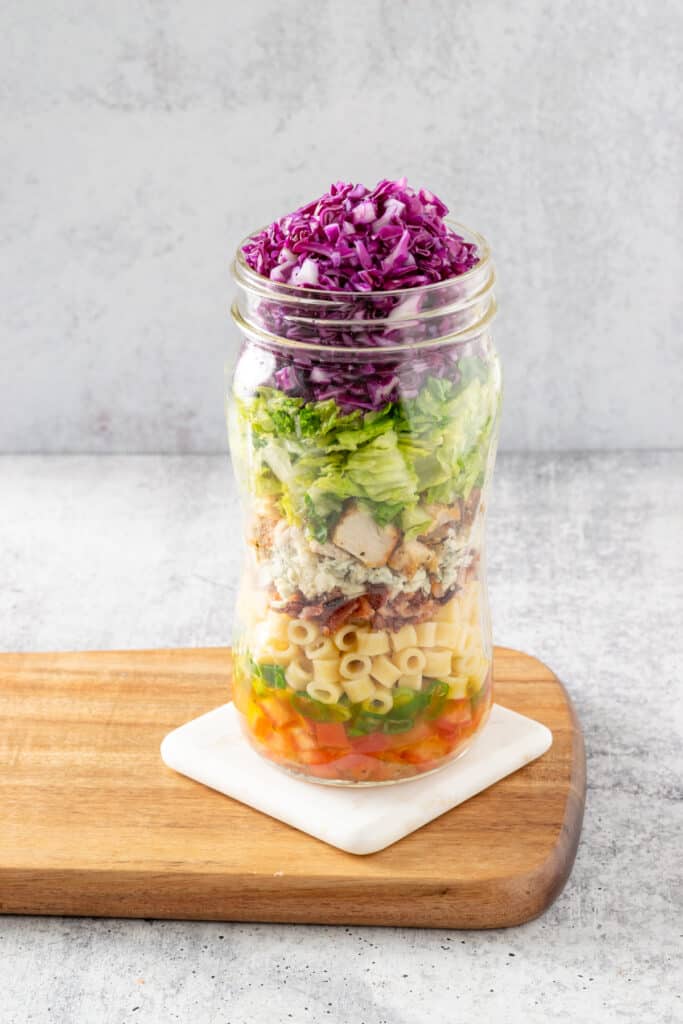 Chopped salad ingredients layered in a mason jar.