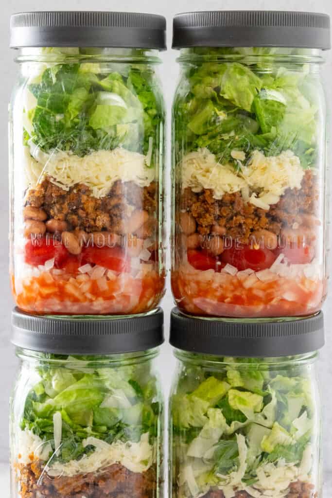 Close up view showing the distinct layers of ingredients in the salad jar, with the salsa on the bottom and lettuce on top.