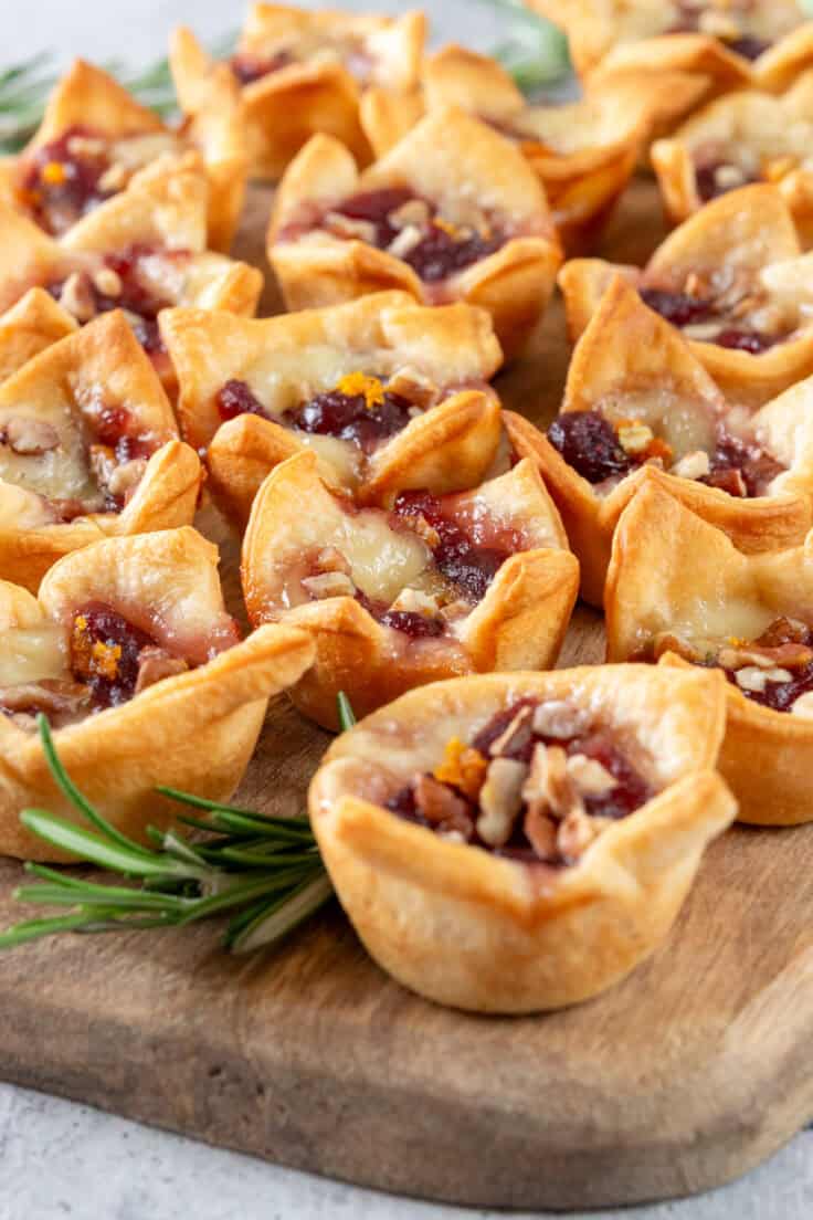 Close up view of cranberry brie bites showing the melted cheese and gooey cranberry sauce with orange zest and pecan chips inside a mini piece of baked crescent roll dough.