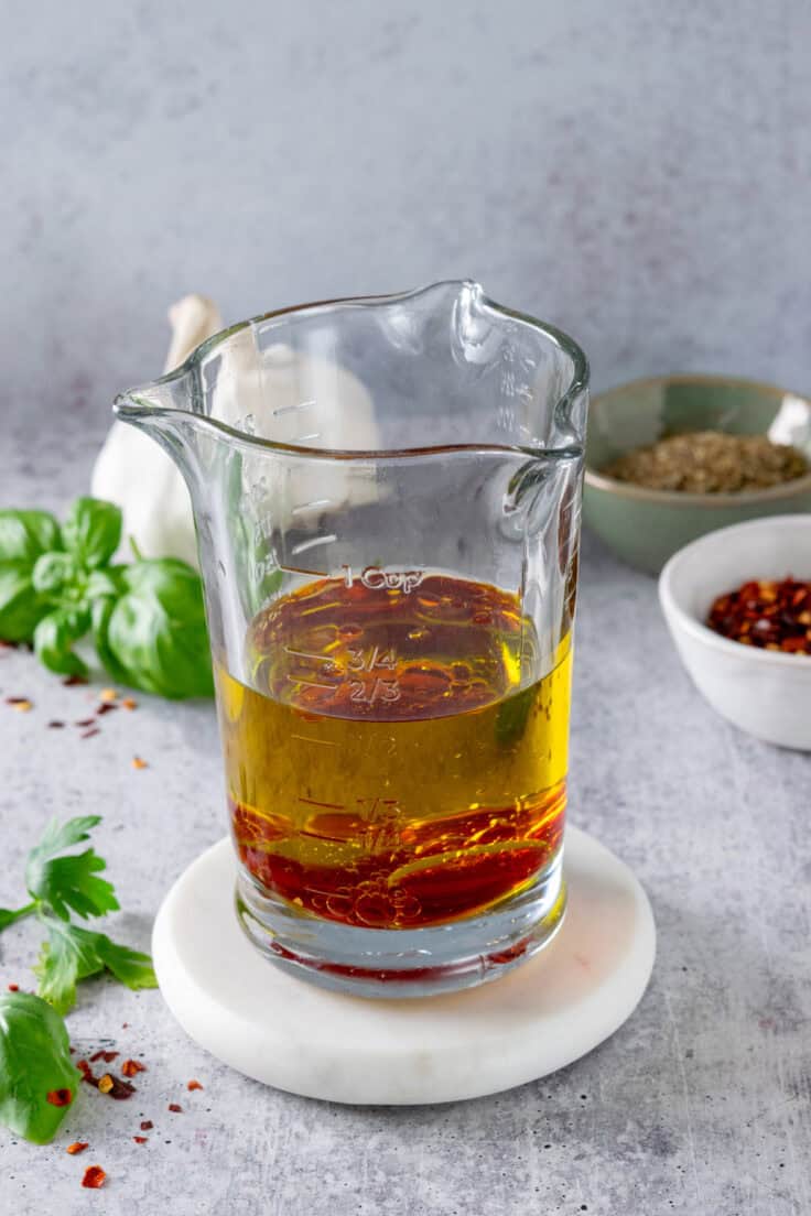 Tall glass measuring cup with olive oil and vinegar in it.