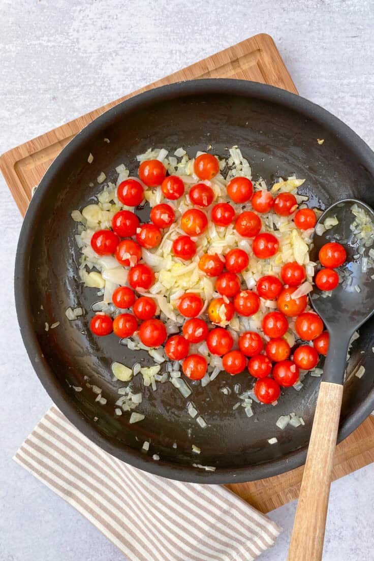 Whole cherry tomatoes added to skillet with onions and garlic.