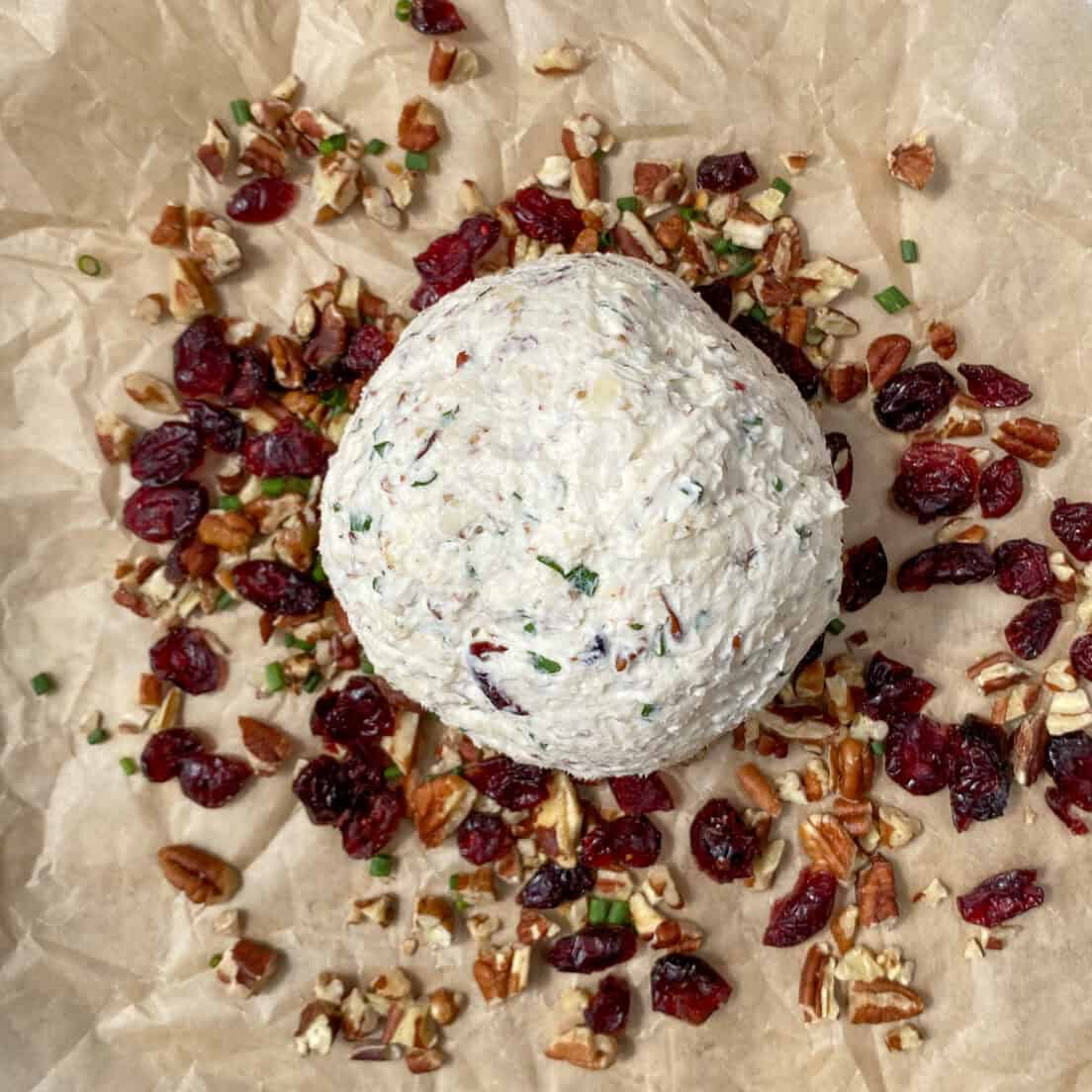 A plain cheese ball sitting on top of the coating mixture ready to be rolled in it.