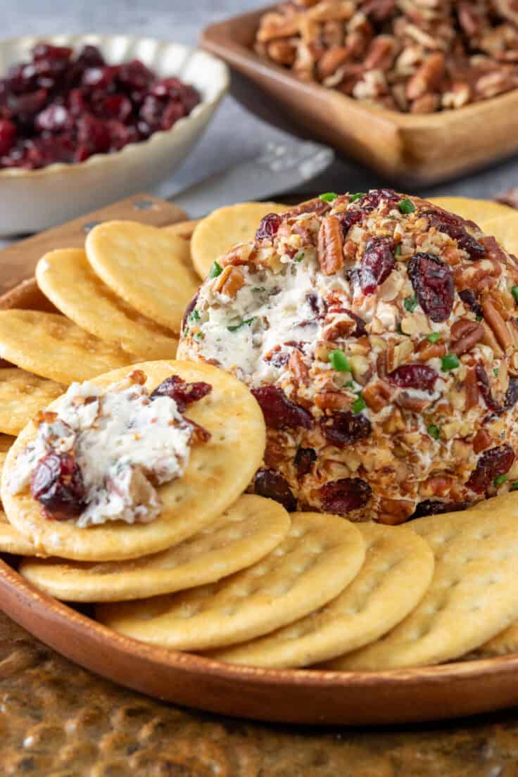 Cranberry pecan cheeseball showing some of the cheese spread onto a cracker.