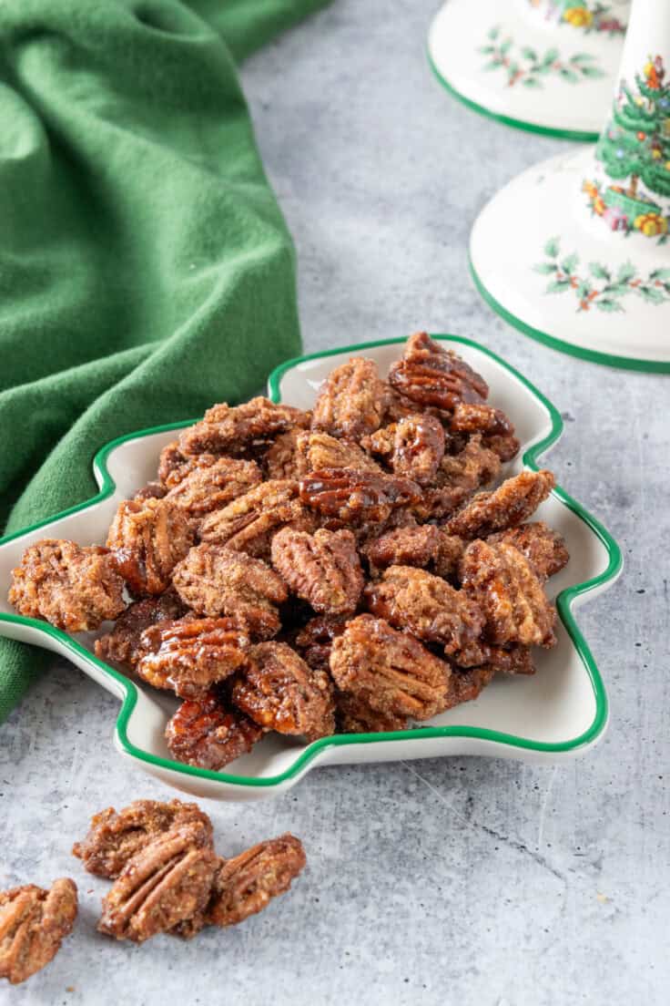 A Christmas tree shaped candy dish full of candied pecans for serving at a holiday party.