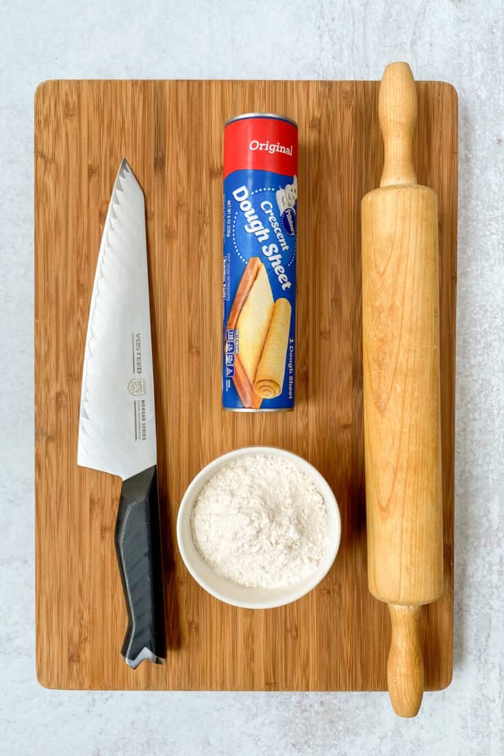 A sharp knife, small bowl of flour, tube of crescent dough sheet and rolling pin.