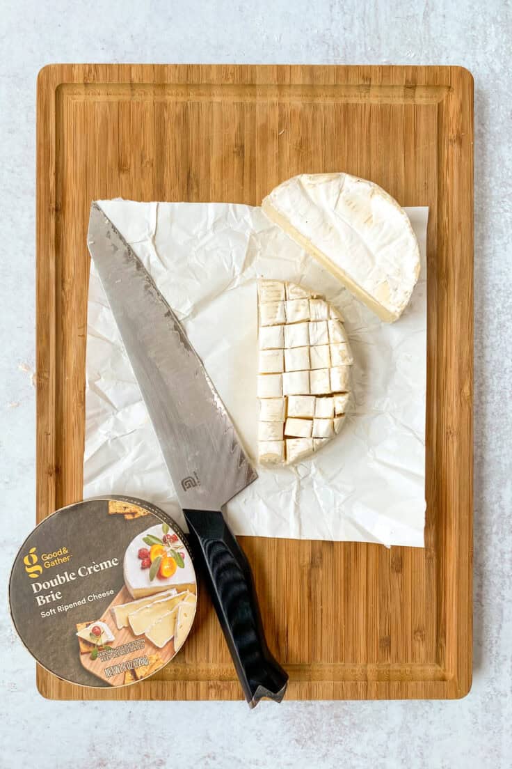 Half a wheel of brie cheese that has been sliced into about twenty-four, half inch pieces.