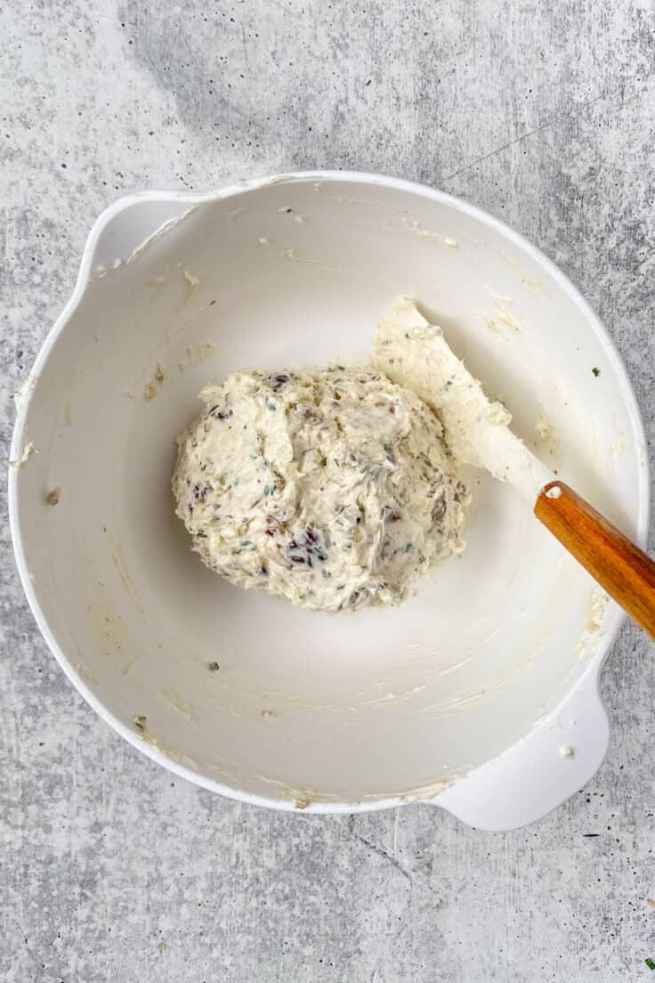 The inside of the cheese ball mixture shaped into a bowl inside the mixing bowl using a rubber spatula.