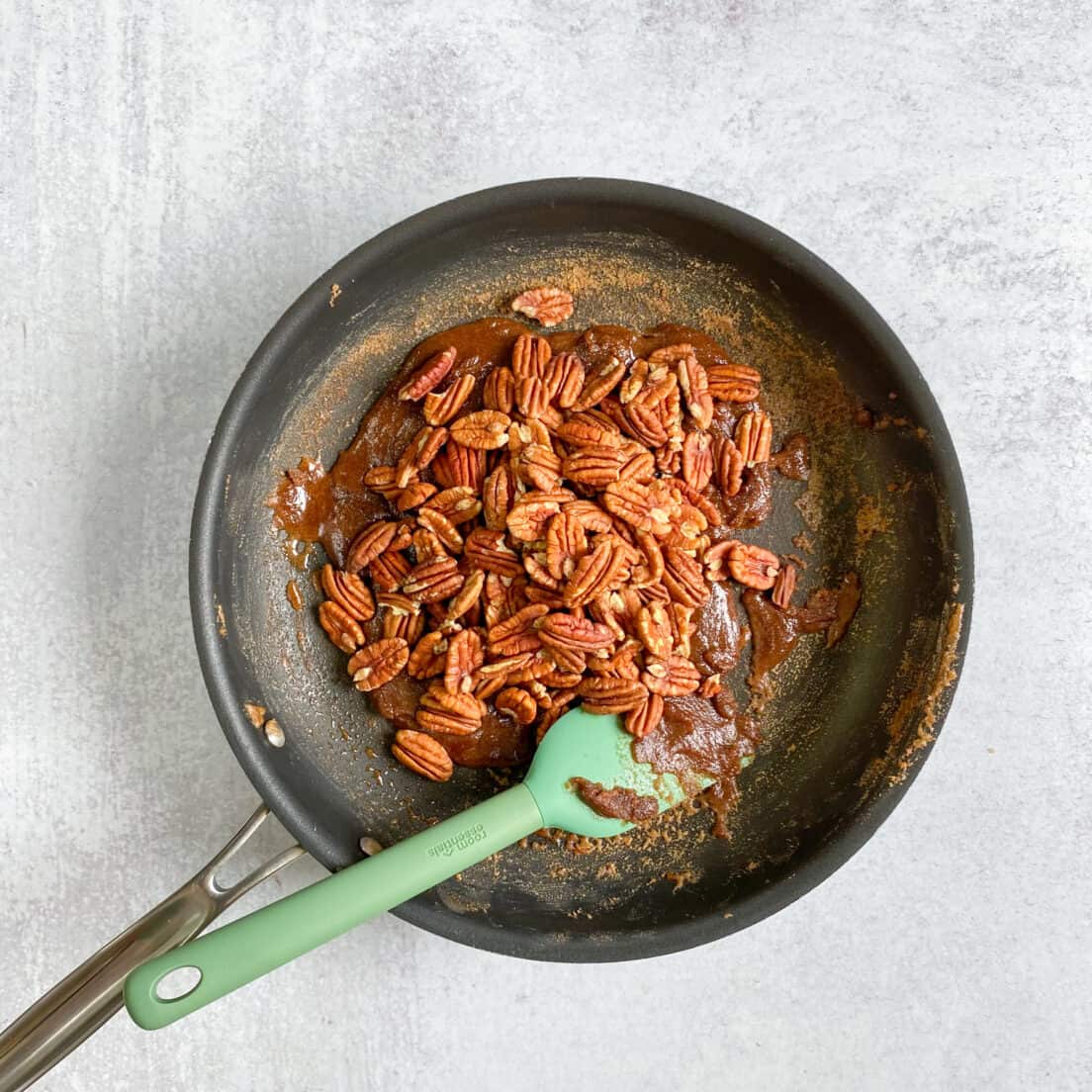 Raw pecans dumped into skillet with hot cinnamon sugar glaze.