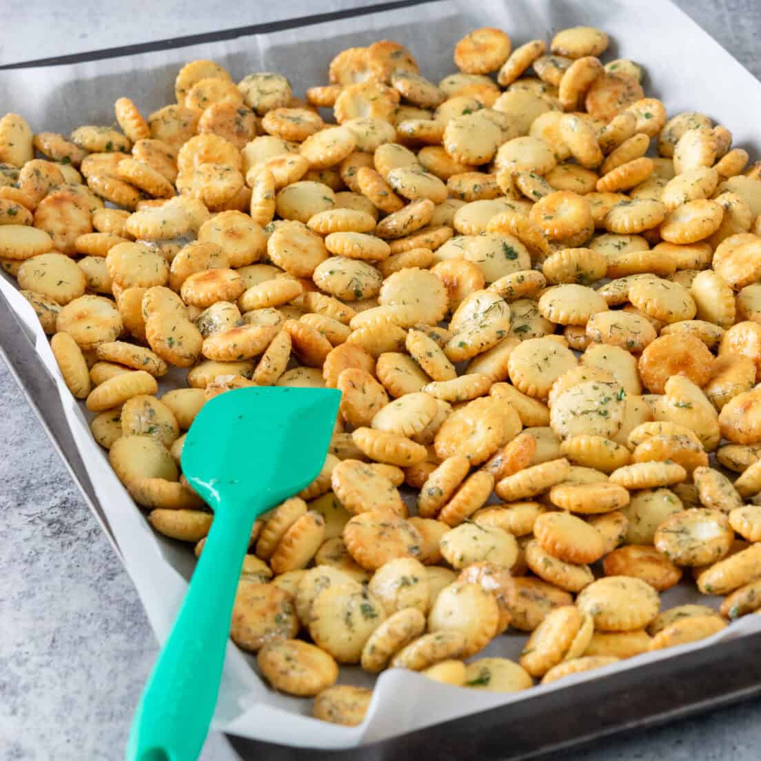 Ranch oyster crackers spread in even layer over baking tray ready to go in the oven.