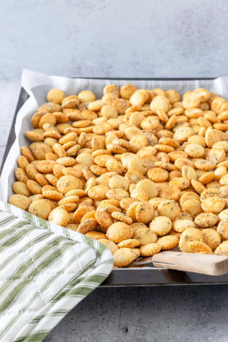 Crisp ranch oyster crackers just out of the oven with a green and white striped pot holder.