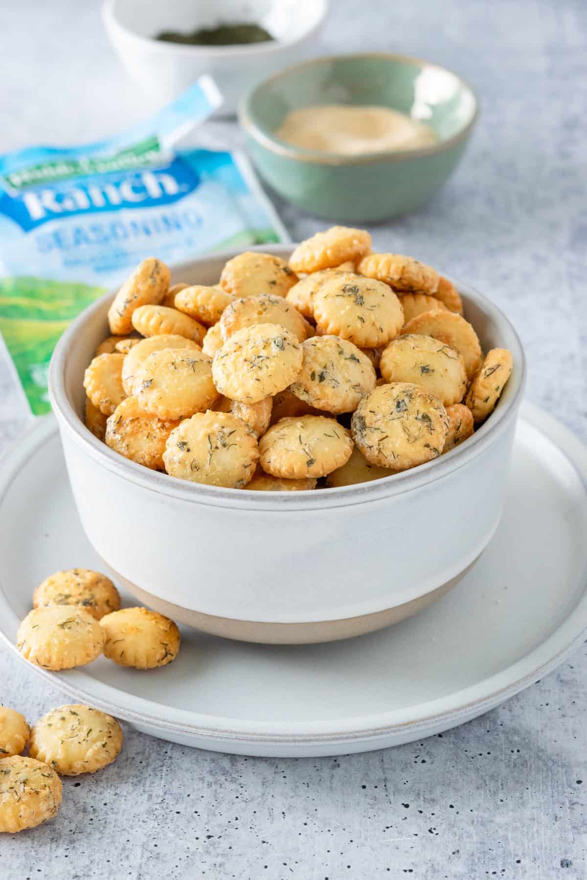 Bowl of ranch oyster crackers next to an envelope of ranch seasoning mix.