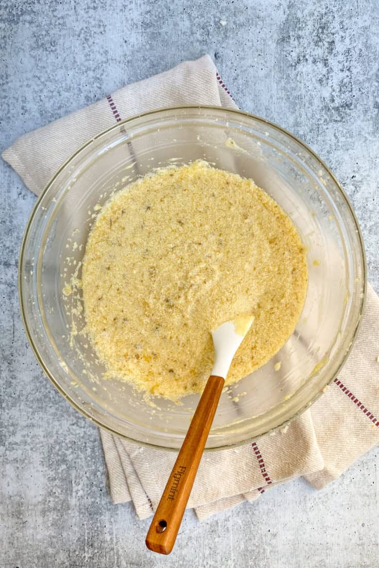 Banana bread wet ingredients all combined in a mixing bowl with a rubber spatula in it.