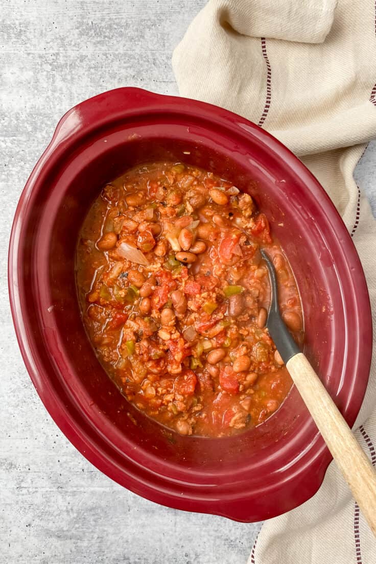 Steaming hot turkey chili in a Crock Pot with a ladle in it.