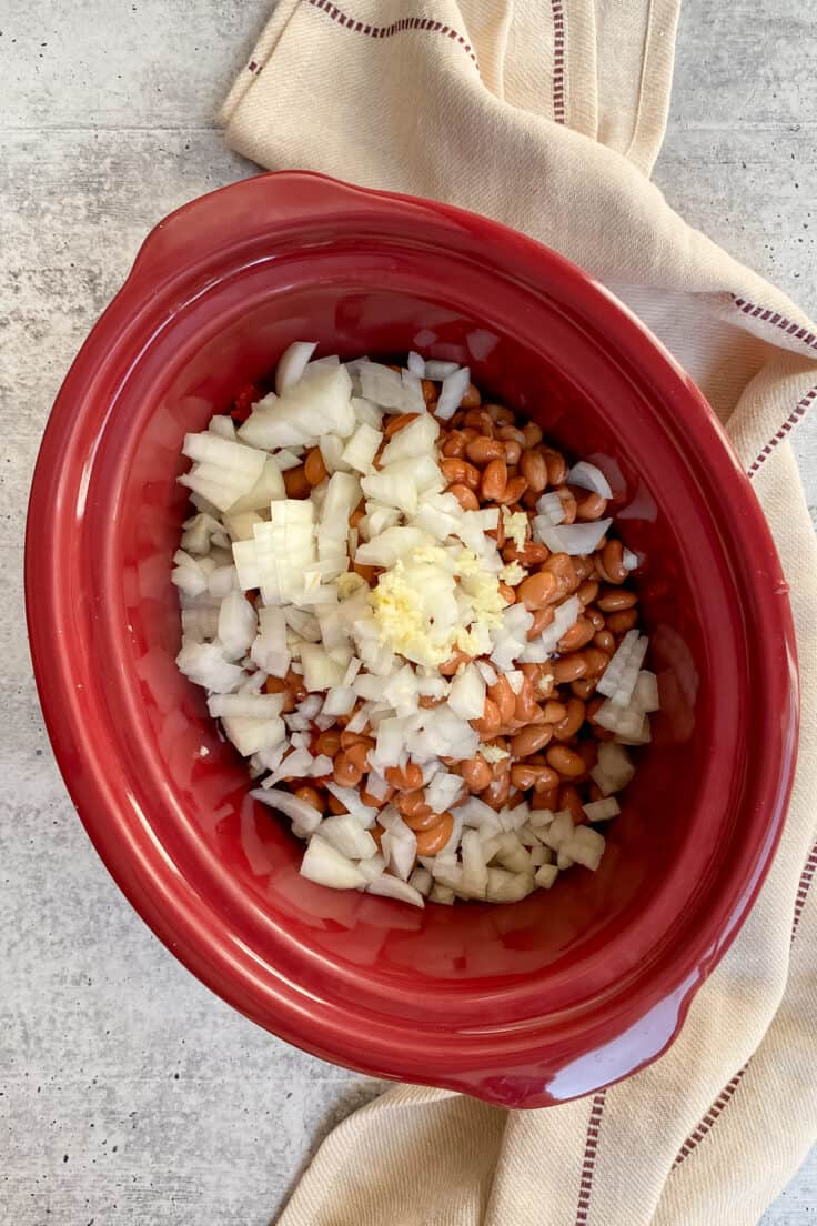 Chopped onion and garlic in Crock Pot with the rest of the slow cooker chili ingredients.