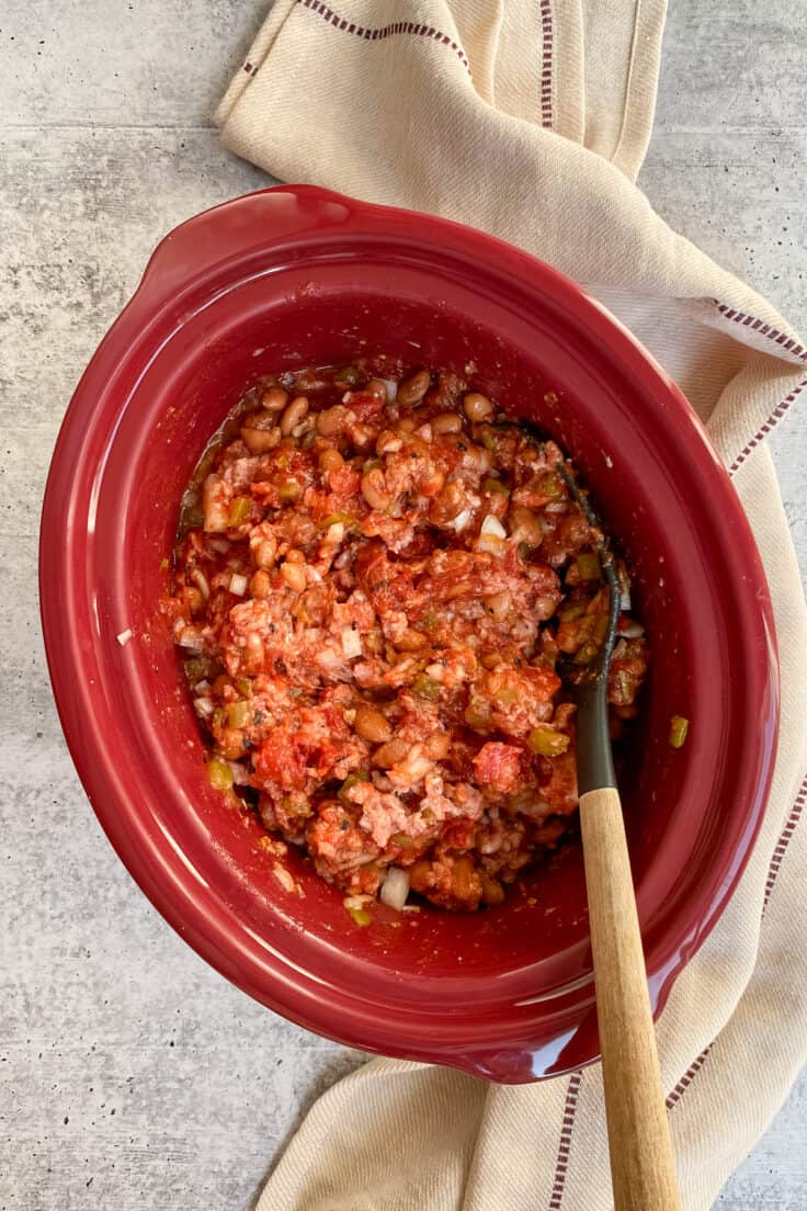 Stirring the chili in a slow cooker before cooking.