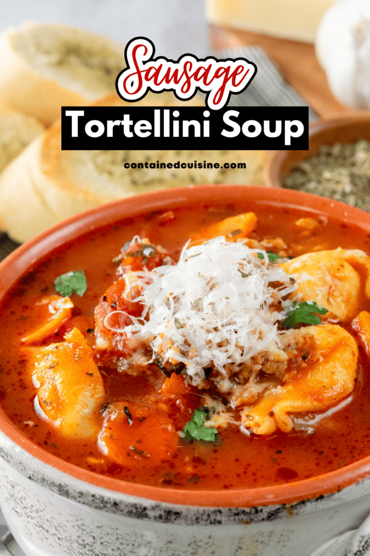 A close-up view of a hearty bowl of homemade sausage tortellini soup with freshly grated parmesan cheese on top.