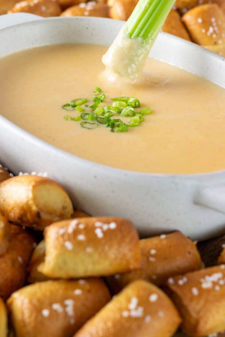 Celery stick being dipped into beer cheese dip.