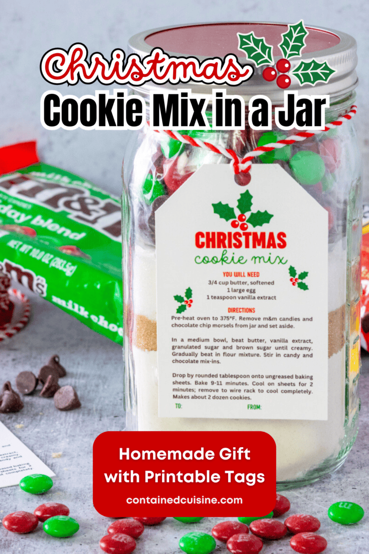 Homemade Christmas cookie mix layered in a mason jar with a gift tag tied on it. The jar is next to a bag of holiday m&m's and some chocolate chips.