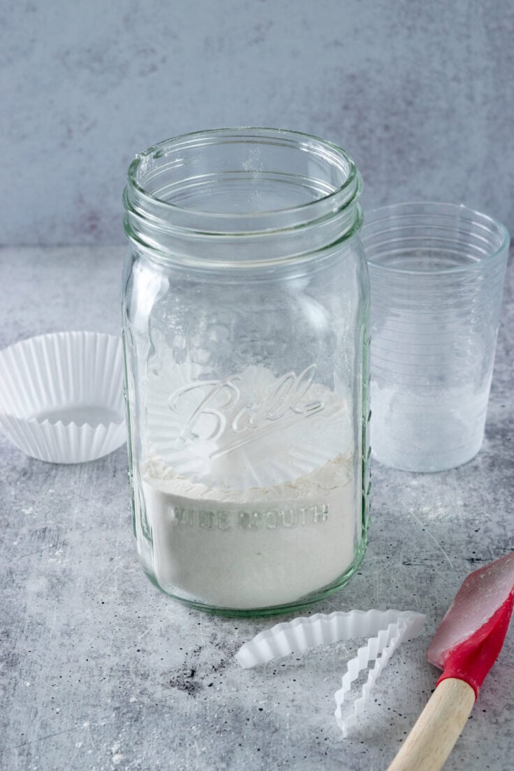 The flour layer of the cookie mix with a paper muffin tin liner on top of it to separate it from the other ingredients that will go on top of it.