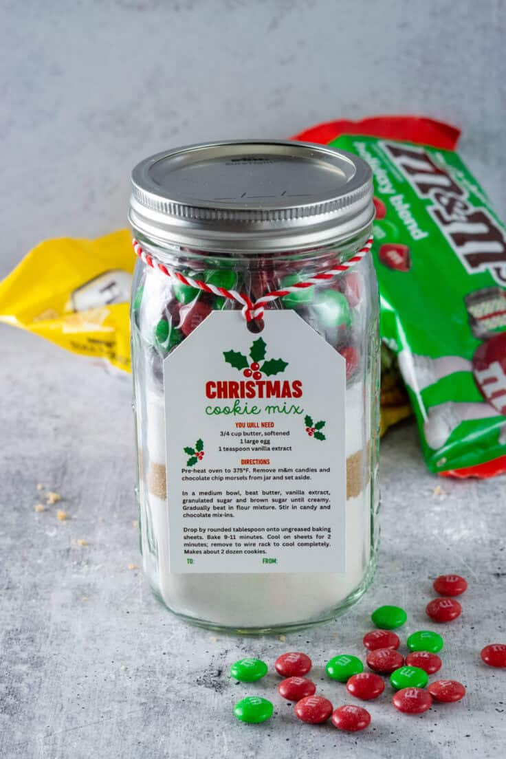 Jar of homemade Christmas cookie mix with a gift tag that, says Christmas cookie mix and has baking instructions, hanging on the jar with Christmas ribbon.