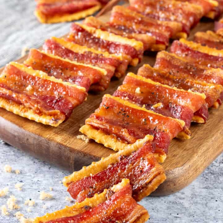 Brown sugar bacon-wrapped club crackers on a serving board for an appetizer.