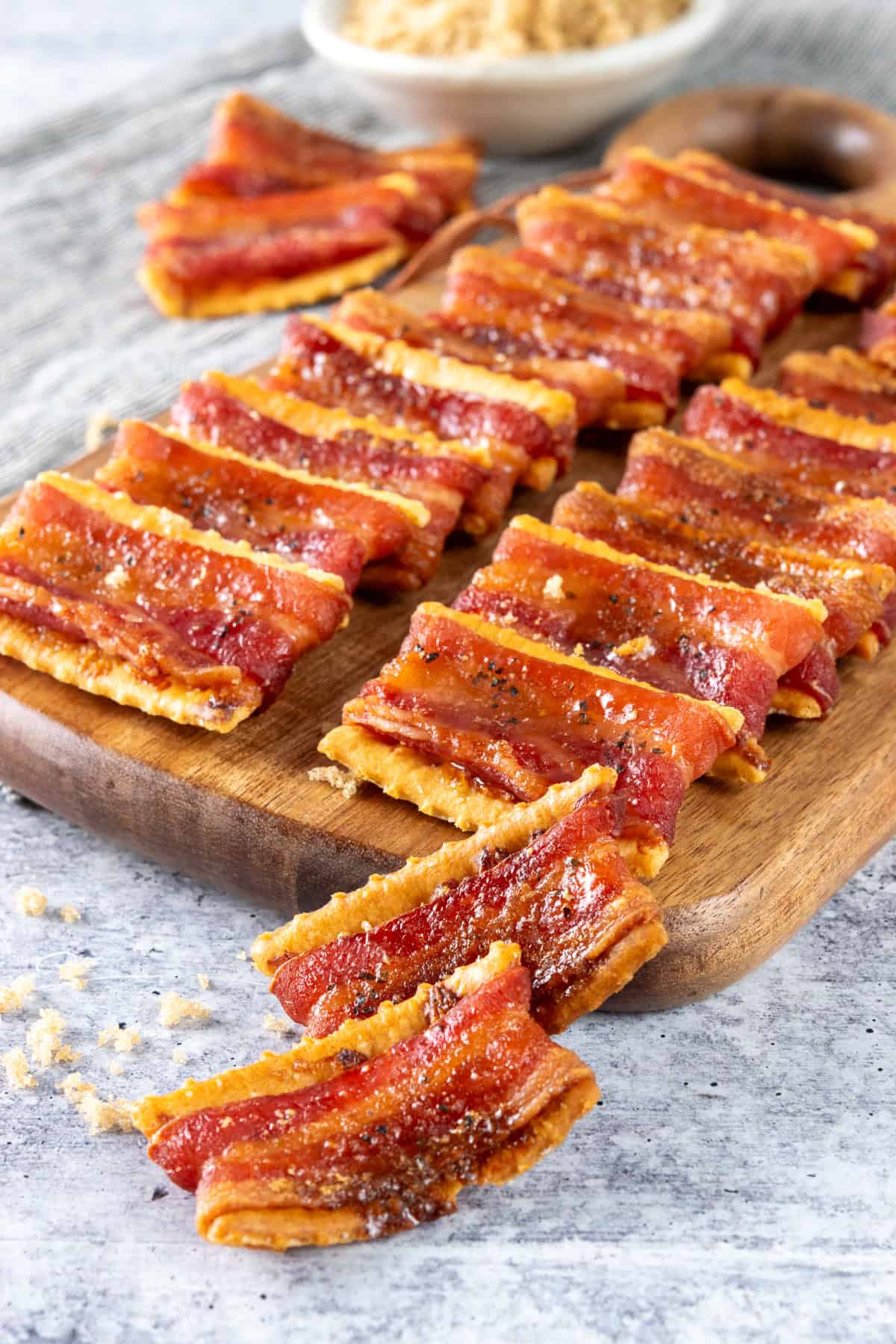 Brown sugar bacon-wrapped club crackers on a serving board for an appetizer.