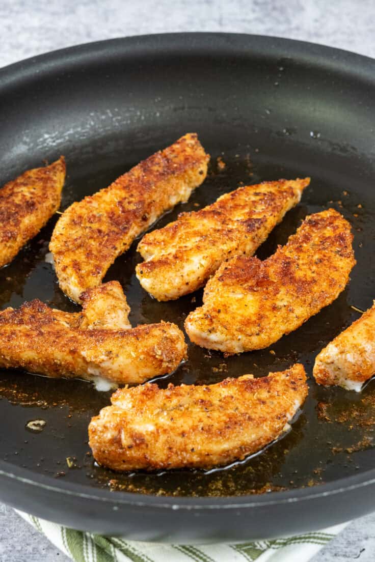 Cooked chicken tenderloins in a skillet with olive oil.