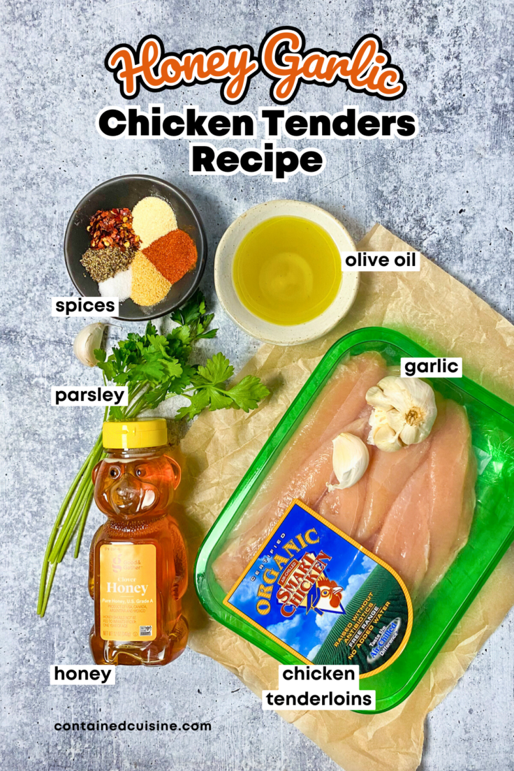 An overhead picture showing all the ingredients needed to make this honey garlic chicken tenders recipe. The image includes a small bowl full of spices, a small bowl of olive oil, flat-leaf parsley, a bottle of honey, some garlic cloves, and a package of raw chicken tenderloins.