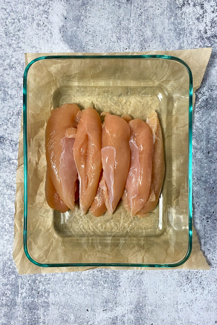 Raw chicken tenderloins in a glass dish with the tendons removed.