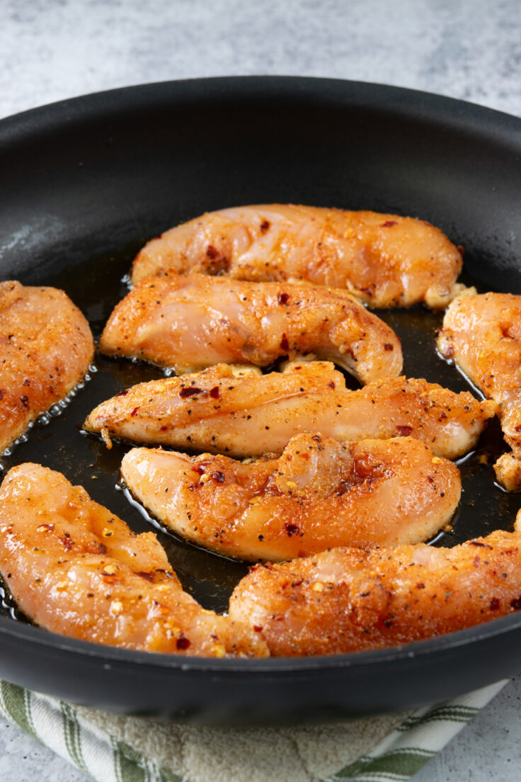 Seasoned chicken added to a hot skillet.