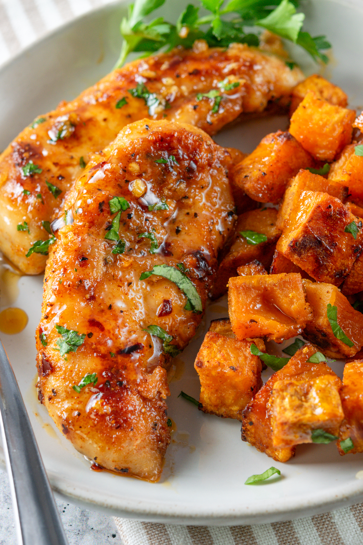 Honey garlic chicken tenders on a dinner plate with roasted sweet potatoes.