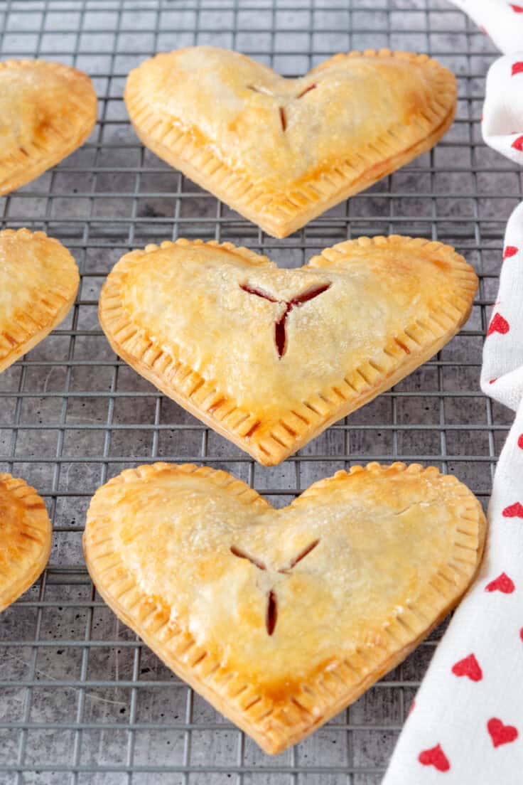 Close-up view of three cherry hand pies cooling on a baking rack.