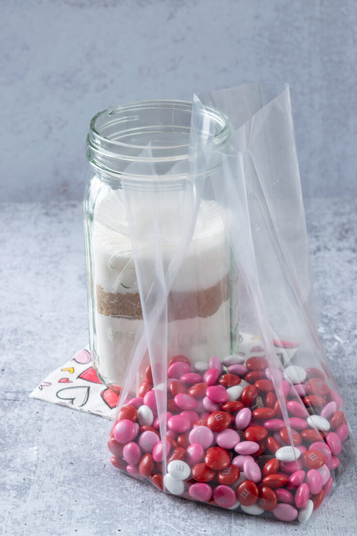 A cellophane bag full of Valentine M&M's and chocolate chips to add into the jar of Valentine's Day cookie mix.