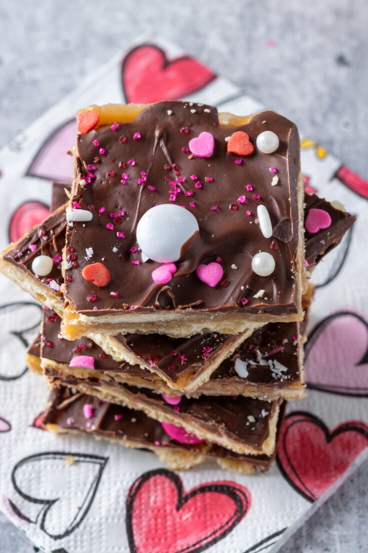 Top view of crack candy decorated for Valentine's Day with heart-shaped sprinkles, pink sugar sparkles and valentine m&m candies.