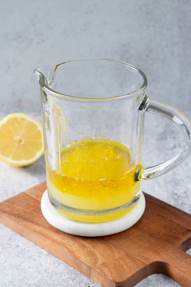 Freshly squeezed lemon juice added to olive oil in a large measuring cup to make homemade dressing.