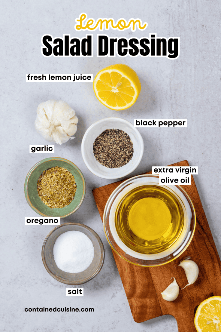 An overhead picture showing all the ingredients needed to make homemade lemon salad dressing, including lemon, garlic, olive oil and small bowls filled with salt, pepper and oregano.