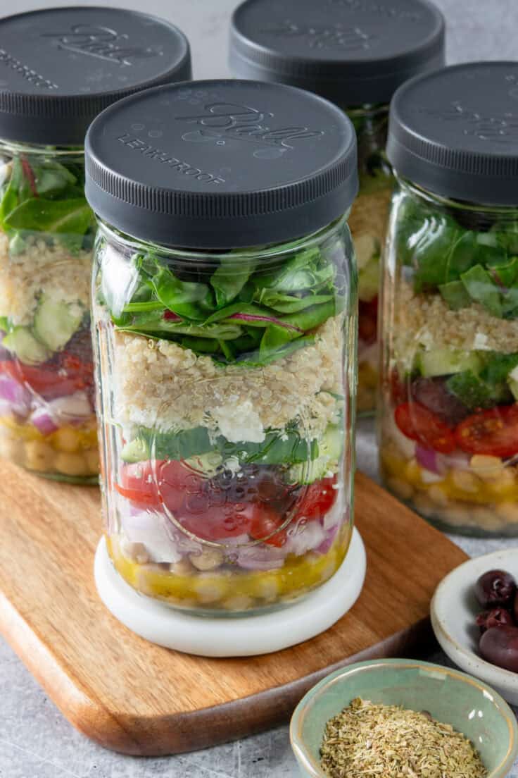 Four mason jar Mediterranean salads with lids on jars.