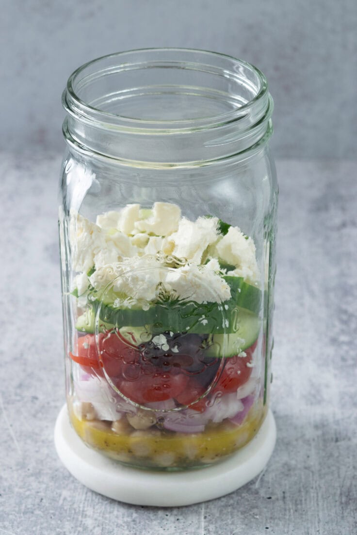 Feta cheese added to mason jar Mediterranean salad.