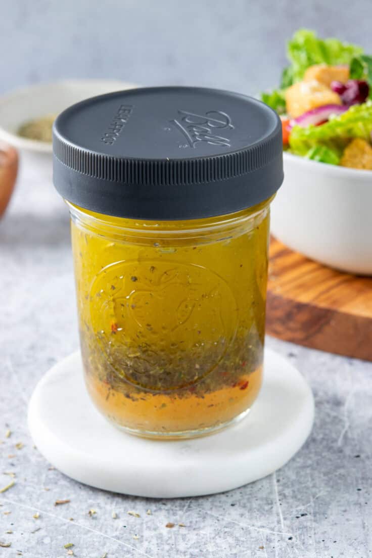 Homemade Italian vinaigrette that's in a small mason jar with a plastic lid. The vinaigrette has separtated.