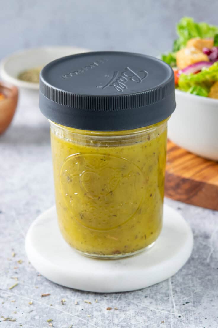 Italian vinaigrette that's in a small mason jar with a plastic lid on it. The dressing has been shaken to combine it before using on salad.