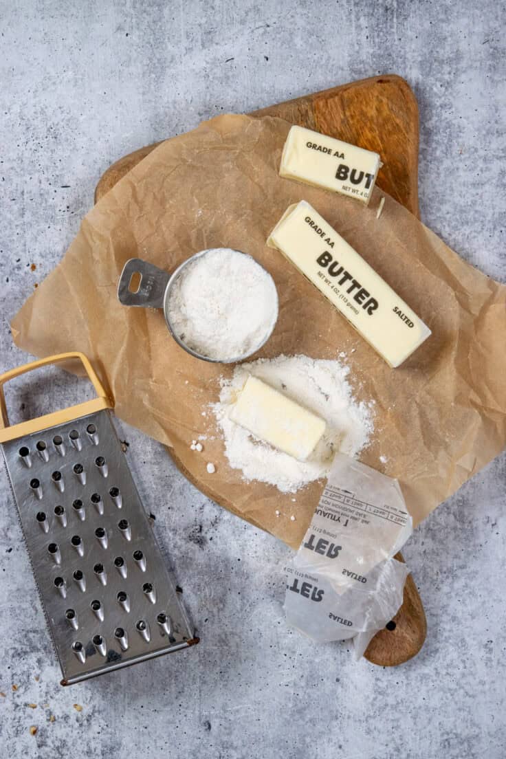 Showing how to grate cold butter to put on top of a dump cake. Half a stick of butter is being rolled in a little bit of cake mix before grating.