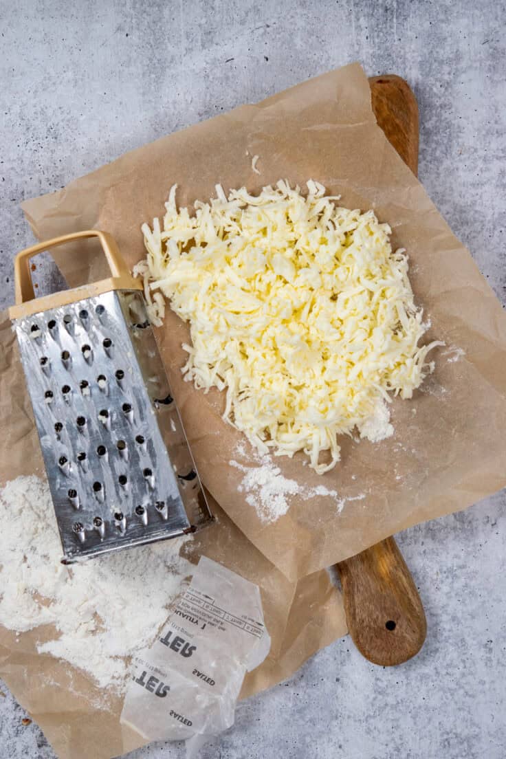 A pile of grated butter next to a box grater, ready to put on top of the dump cake.