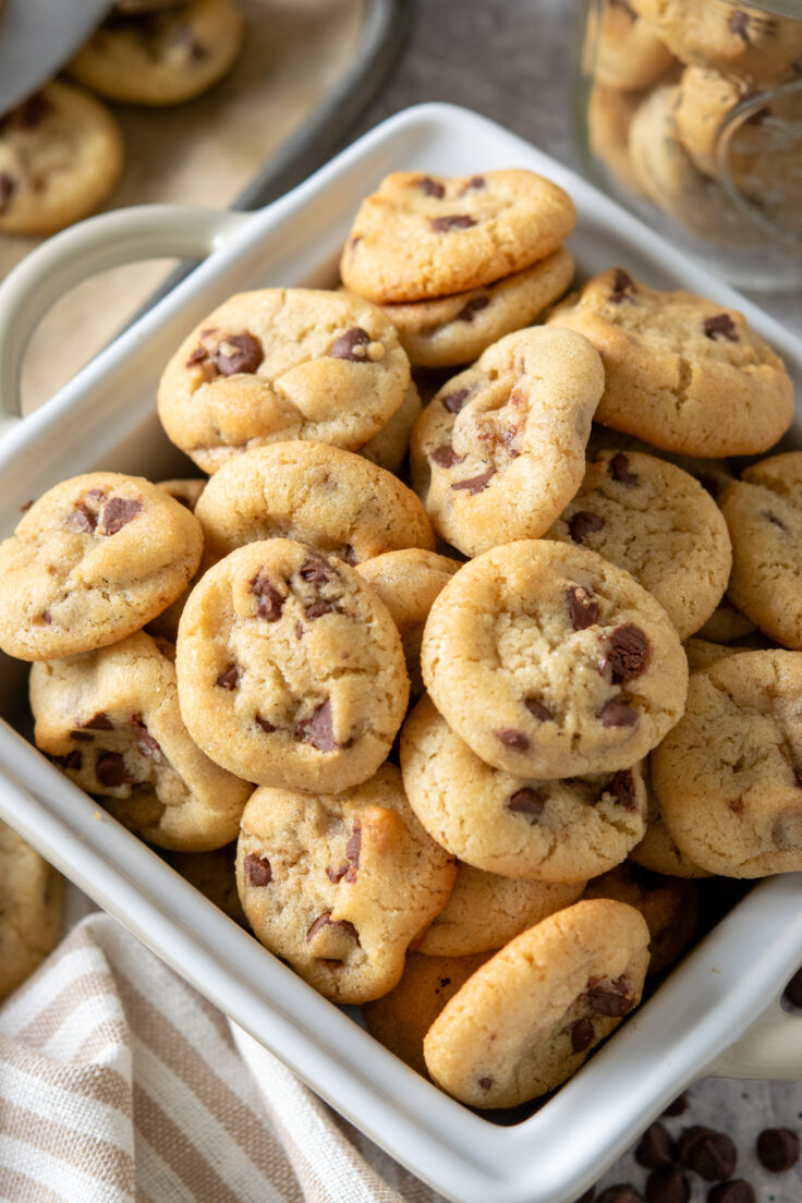 A close-up view of a tray piled high with moist and chewy mini chocolate chip cookies.